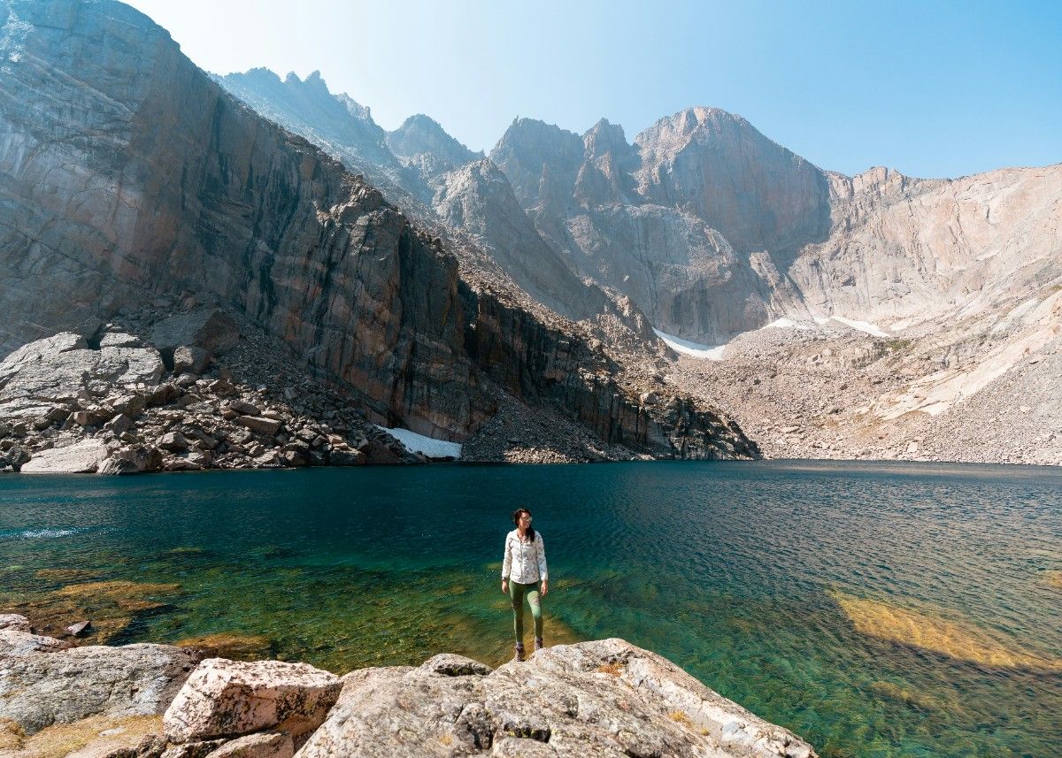 A person stood in front of the lake and mountainous landscape of Rocky Mountain National Park 