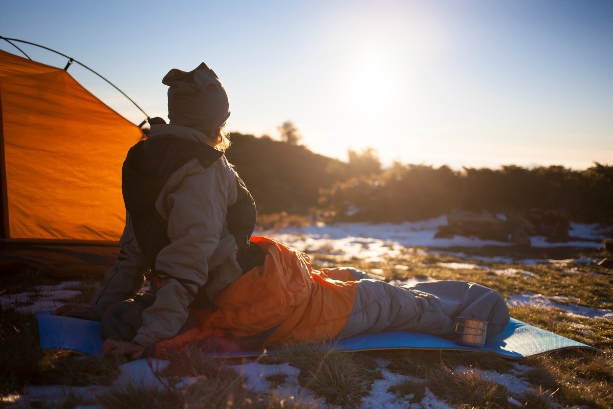 Woman in her sleeping bag next to her tent