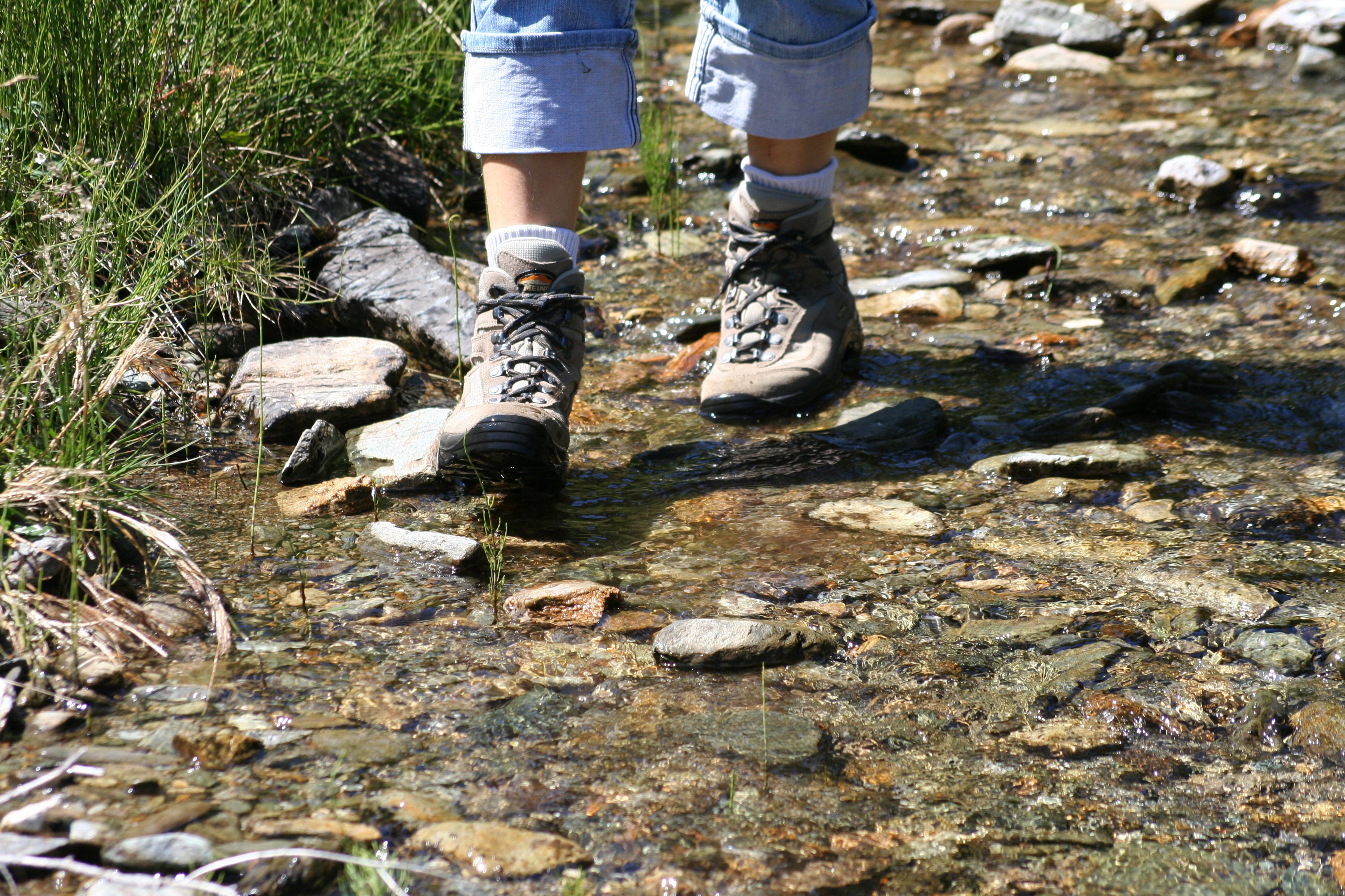 Hiker wearing walking boots and crossing stream