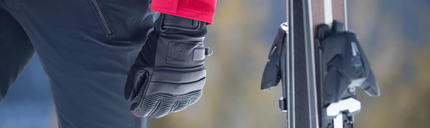 A person wearing ski gloves next to their skis